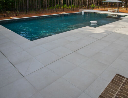 Modern porcelain pavers complementing an alluring pool and a cozy gas fireplace