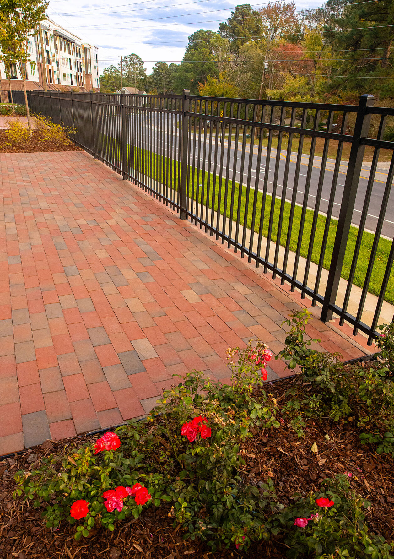 Pine Hall Brick paver patio with landscaping and black metal fencing at Peterson Station at Sunset Lake.
