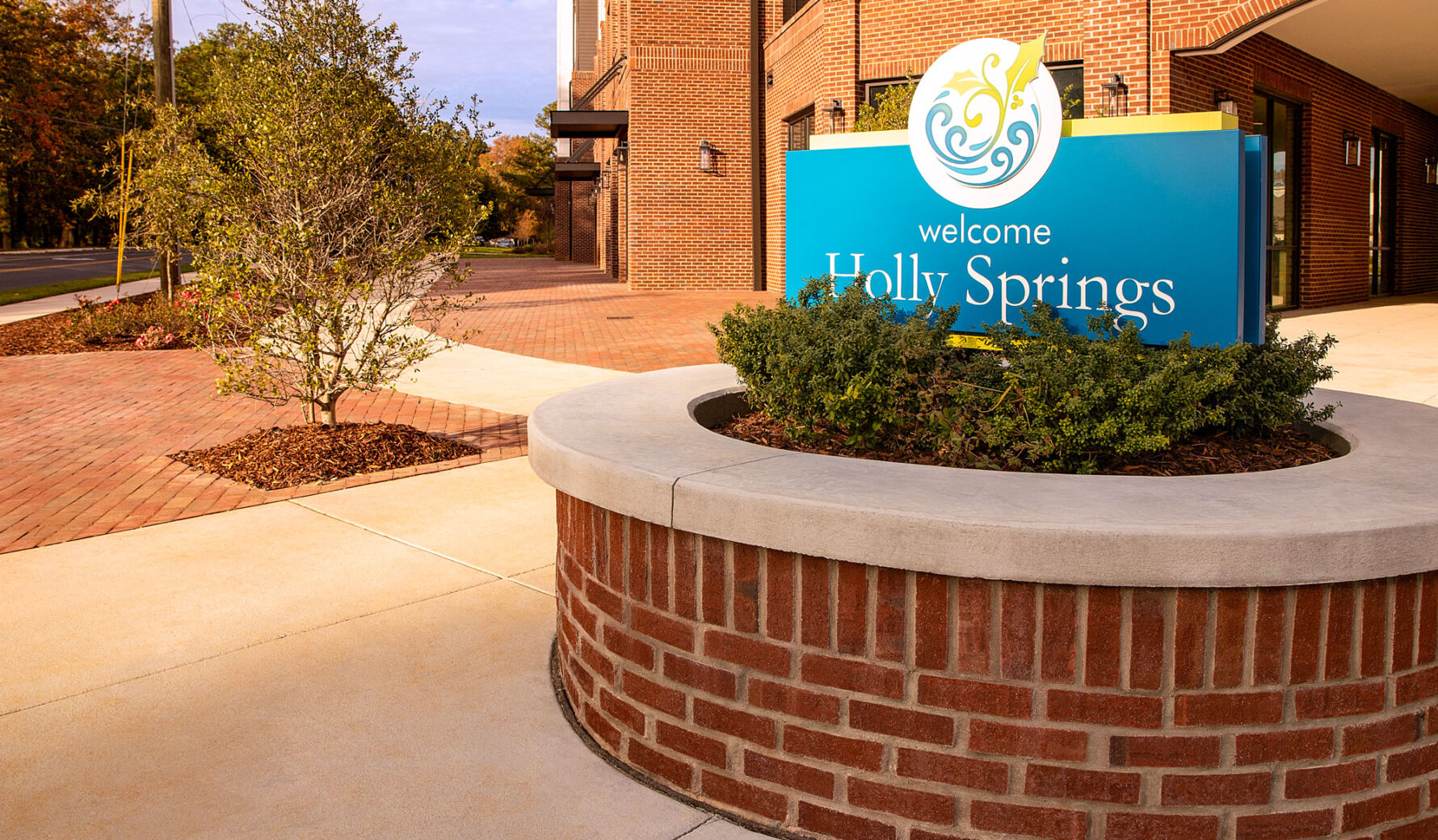 Holly Springs welcome sign with masonry monument sign structure, brick veneer, and paver walkways at Peterson Station at Sunset Lake.